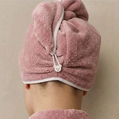 Pink hair dryer turban worn by a person on a beige background