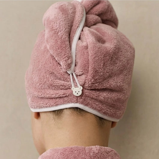 Pink hair dryer turban worn by a person on a beige background