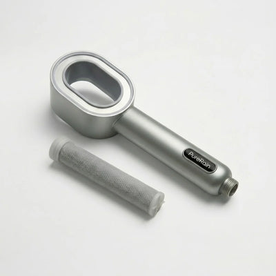 Silver handheld filtered shower head on a white background pictured next to a filter that is normally inside the showerhead, featuring the 'PureRain' brand.