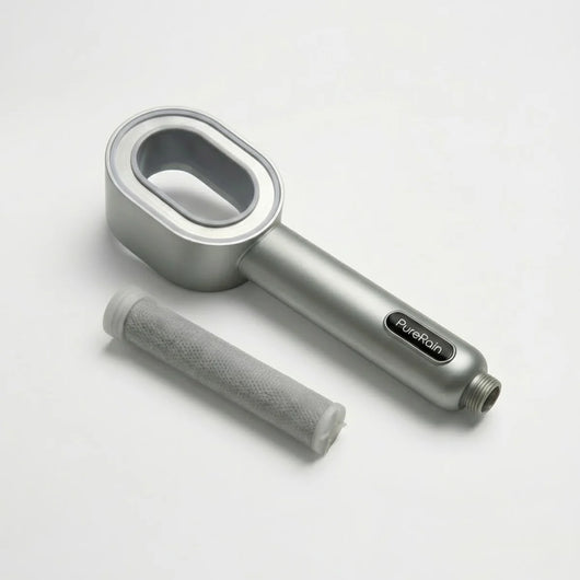 Silver handheld filtered shower head on a white background pictured next to a filter that is normally inside the showerhead, featuring the 'PureRain' brand.